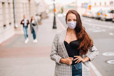 Covid-19 ve Hava kirliliği pm2.5 konsepti. Salgın, sokakta koruyucu maske takan genç bir kadının portresi. Sağlık ve güvenlik kavramını