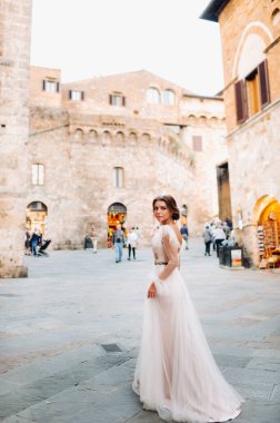 San Gimignano 'nun eski kasabasında beyaz elbiseli bir gelin. İtalya' da bir kız dolaşıyor. Toskana 'da.