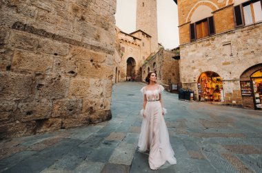 San Gimignano 'nun eski kasabasında beyaz elbiseli bir gelin. İtalya' da bir kız dolaşıyor. Toskana 'da.