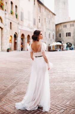 San Gimignano 'nun eski kasabasında beyaz elbiseli bir gelin. İtalya' da bir kız dolaşıyor. Toskana 'da.