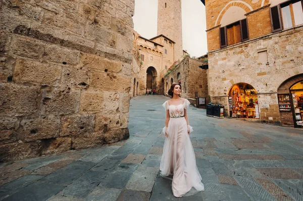 San Gimignano 'nun eski kasabasında beyaz elbiseli bir gelin. İtalya' da bir kız dolaşıyor. Toskana 'da.