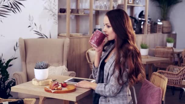Egy lány kávét iszik egy kávézóban, gyönyörű haja van egy lánynak. — Stock videók