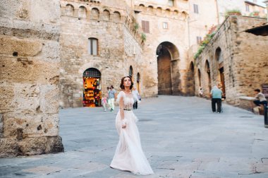 San Gimignano 'nun eski kasabasında beyaz elbiseli bir gelin. İtalya' da bir kız dolaşıyor. Toskana 'da.