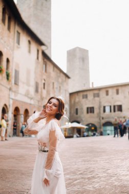San Gimignano 'nun eski kasabasında beyaz elbiseli bir gelin. İtalya' da bir kız dolaşıyor. Toskana 'da.