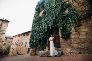San Gimignano 'nun eski kasabasında beyaz elbiseli bir gelin. İtalya' da bir kız dolaşıyor. Toskana 'da.
