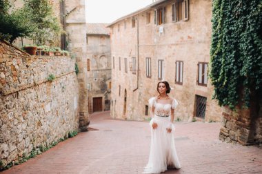 San Gimignano 'nun eski kasabasında beyaz elbiseli bir gelin. İtalya' da bir kız dolaşıyor. Toskana 'da.