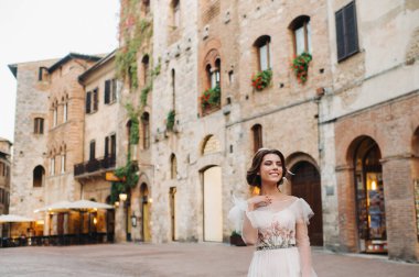 San Gimignano 'nun eski kasabasında beyaz elbiseli bir gelin. İtalya' da bir kız dolaşıyor. Toskana 'da.