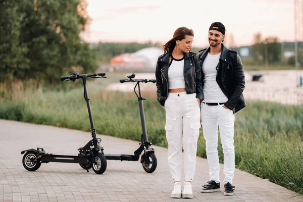 portrait of a couple sitting near electric scooters, enjoying time in nature together, Two lovers on electric scooters.People on scooters.