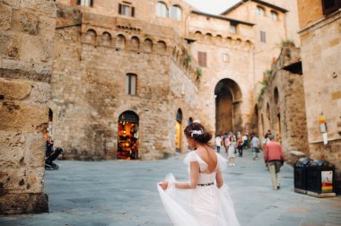 San Gimignano 'nun eski kasabasında beyaz elbiseli bir gelin. İtalya' da bir kız dolaşıyor. Toskana 'da.