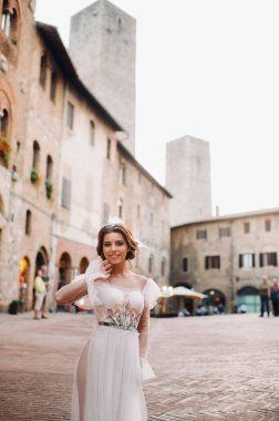 San Gimignano 'nun eski kasabasında beyaz elbiseli bir gelin. İtalya' da bir kız dolaşıyor. Toskana 'da.