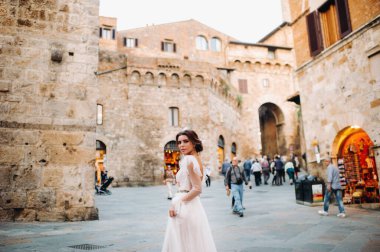 San Gimignano 'nun eski kasabasında beyaz elbiseli bir gelin. İtalya' da bir kız dolaşıyor. Toskana 'da.