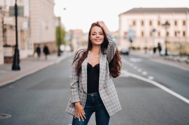 Ceketli ve uzun saçlı bir kız eski şehirde yürüyor. Güzel bir kız gülümsüyor. Yoldaki kız..