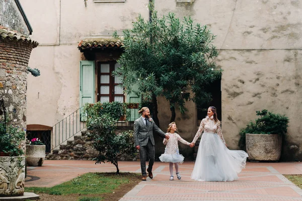 A happy young family walks through the old town of Sirmione in Italy.Stylish family in Italy on a walk.