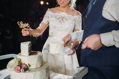 Gelin ve damat düğün pastalarını kestiler. Kesik ve görünür dolgusu olan güzel bir pasta. Düğün pastasında aşk kelimesi, düğün konsepti...