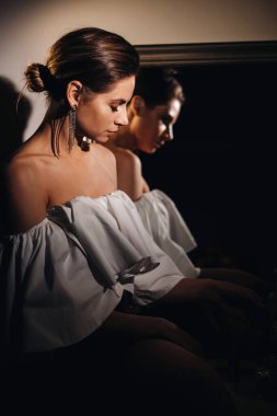 Evdeki ayna yansımasında güzel bir kız. Tatilden önce aynanın yanında bir kız. Uzun saçlı beyaz elbiseli bir kız evde bir partiye gidiyor..