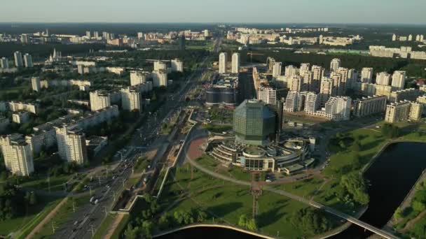 Blick von oben auf die Nationalbibliothek und ein neues Viertel mit einem Park in Minsk bei Sonnenuntergang. Weißrussland, öffentliches Gebäude — Stockvideo