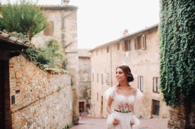 San Gimignano 'nun eski kasabasında beyaz elbiseli bir gelin. İtalya' da bir kız dolaşıyor. Toskana 'da.