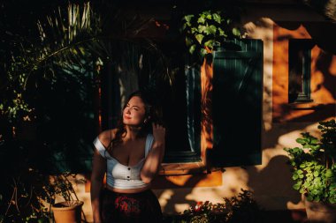 Beyaz tişörtlü bir kız Fransa 'da eski bir evin penceresinin önünde duruyor. Kız gülümsüyor, Fransız kasabasının eteğindeki pencerede oturuyor. Provence..