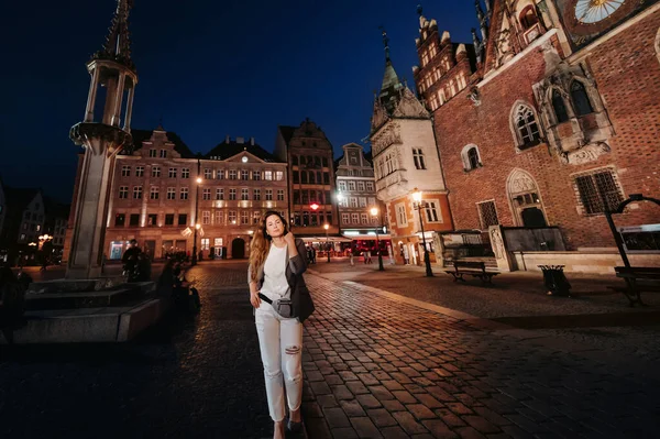 深夜时分 一个浪漫的女孩在波兰的老城弗罗茨拉夫散步 在波兰的老城 一个穿着长裤和夹克的女人在散步 — 图库照片