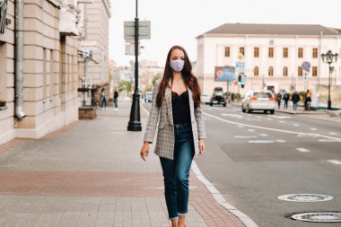 Covid-19 ve Hava kirliliği pm2.5 konsepti. Salgın, sokakta koruyucu maske takan genç bir kadının portresi. Sağlık ve güvenlik kavramını