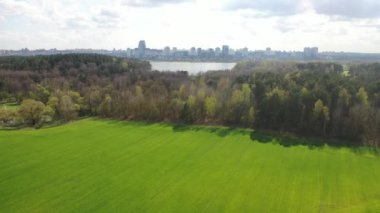 Yeşil ekili bir arazi ve Minsk manzaralı bir park üzerinde yavaş uçuş. 4K İHA görüntüsü. Beyaz Rusya.