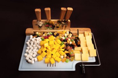 Dilimlenmiş bir tahtada peynirli ve kurutulmuş meyveli peynir tabağı. Peyniri peynirle ve kurutulmuş meyvelerle dilimlemek için özel bir kurul..