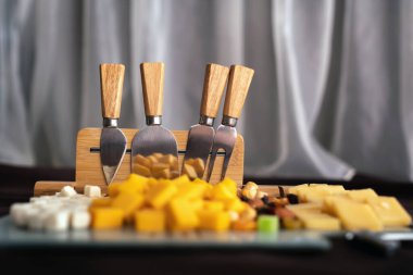 Dilimlenmiş bir tahtada peynirli ve kurutulmuş meyveli peynir tabağı. Peyniri peynirle ve kurutulmuş meyvelerle dilimlemek için özel bir kurul..