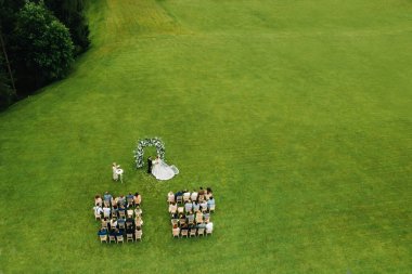 Top view of the Wedding ceremony in a green field with guests sitting on chairs. Wedding venue on the green lawn clipart