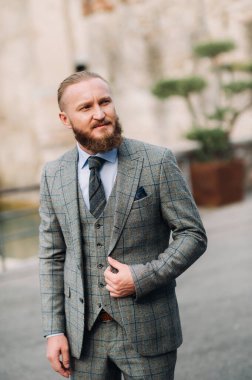 Katı gri takım elbiseli, sakallı bir adam Sirmione 'nin eski kasabasında kravat takıyor. İtalya' da gri takım elbiseli şık bir adam..