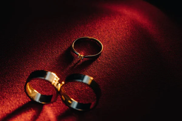 Two Wedding Rings One Engagement Ring Red Background Three Gold — Stock Photo, Image