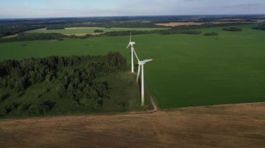 Yel değirmenleri yazın yeşil bir alanda. Ormanın yakınındaki bir tarlada duran büyük yel değirmenleri. Avrupa, Belarus