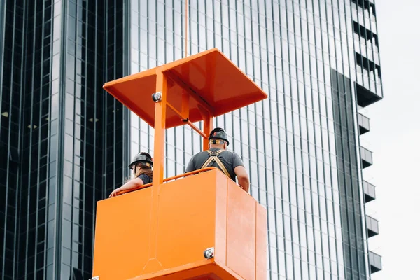 Arbeiders Een Bouwwieg Klimmen Een Kraan Naar Een Groot Glazen — Stockfoto