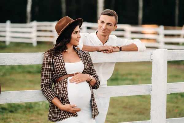 Těhotná Dívka Klobouku Její Manžel Bílém Oblečení Stojí Vedle Ohrady — Stock fotografie