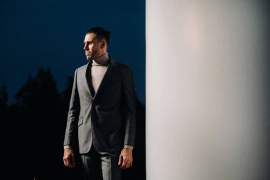 Gri takım elbiseli bir adam gün batımından sonra yel değirmeninin yanında duruyor. Gece değirmenlerinin yakınında bir iş adamı. Modern gelecek kavramı.