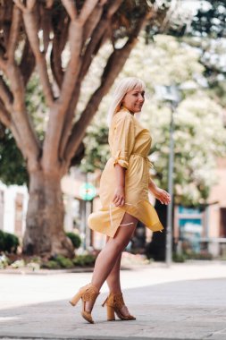 Sarı elbiseli sarışın bir kadın Tenerife.İspanya, Kanarya Adaları 'ndaki La Laguna Eski Kasabası' nın caddesinde duruyor..