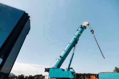 Mavi vinç kaldırma mekanizması, modern binanın yanındaki kancalarla vinç ve hidrolik kaldırma mekanizması 120 metreye kadar çıkıyor..