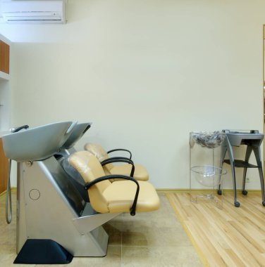 Berber dükkanında saç yıkama sandalyesi. Bir berber dükkanının içinde. Zalim bir yer. Bir güzellik salonunda bej derili sandalye.