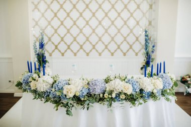 Gelin ve damat masasında bir sürü çiçek var..