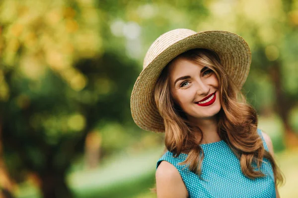 portrait Of a fashionable girl in a blue dress and elegant hat in the Park.
