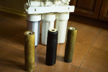 Ev suyu arıtma sistemindeki filtreleri değiştiriyorum. Duma koşullarında su filtreleme için kurulum arka planında kullanılan filtreler.