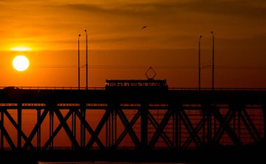 Gün batımında Dnipro nehrinin üzerindeki köprü manzarası. Gün batımı güneşi bulutların arasında çok güzel görünüyor..