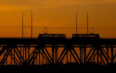 Gün batımında Dnipro nehrinin üzerindeki köprü manzarası. Gün batımı güneşi bulutların arasında çok güzel görünüyor..