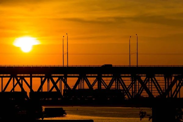 夕暮れ時に川Dnipro上の橋のビュー 夕日は雲の中からとても美しく見えます — ストック写真