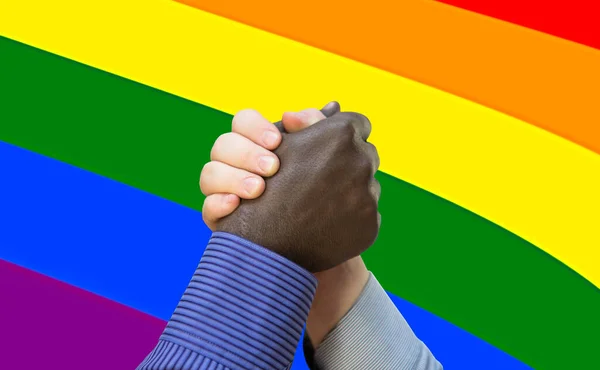 Black lives matter. Close up photo of a handshake between afroamerican and european hands. Handshake in front of LGBT flag.