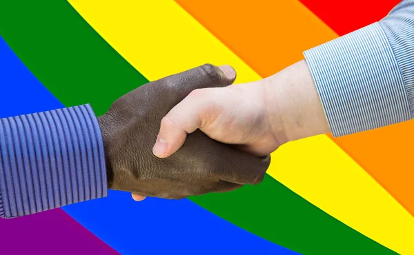 Black lives matter. Close up photo of a handshake between afroamerican and european hands. Handshake in front of LGBT flag.