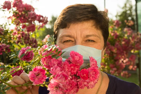 Picture of a middle-aged woman. Protection against coronavirus can also be beautiful. A woman has decorated the medical mask with roses.