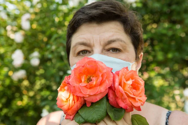 Picture of a middle-aged woman. Protection against coronavirus can also be beautiful. A woman has decorated the medical mask with roses.