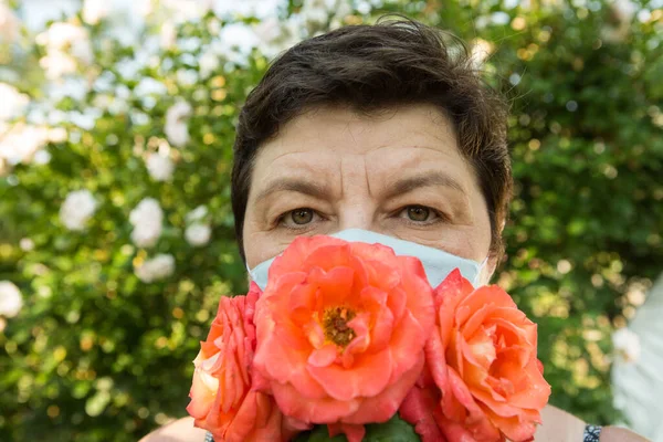 Picture of a middle-aged woman. Protection against coronavirus can also be beautiful. A woman has decorated the medical mask with roses.