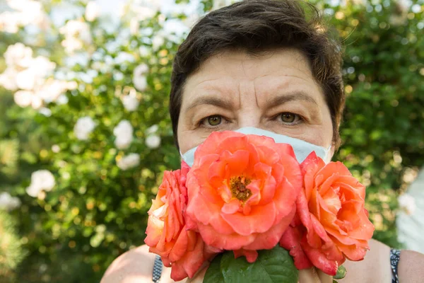Picture of a middle-aged woman. Protection against coronavirus can also be beautiful. A woman has decorated the medical mask with roses.