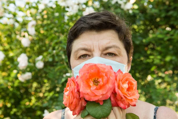 Picture of a middle-aged woman. Protection against coronavirus can also be beautiful. A woman has decorated the medical mask with roses.